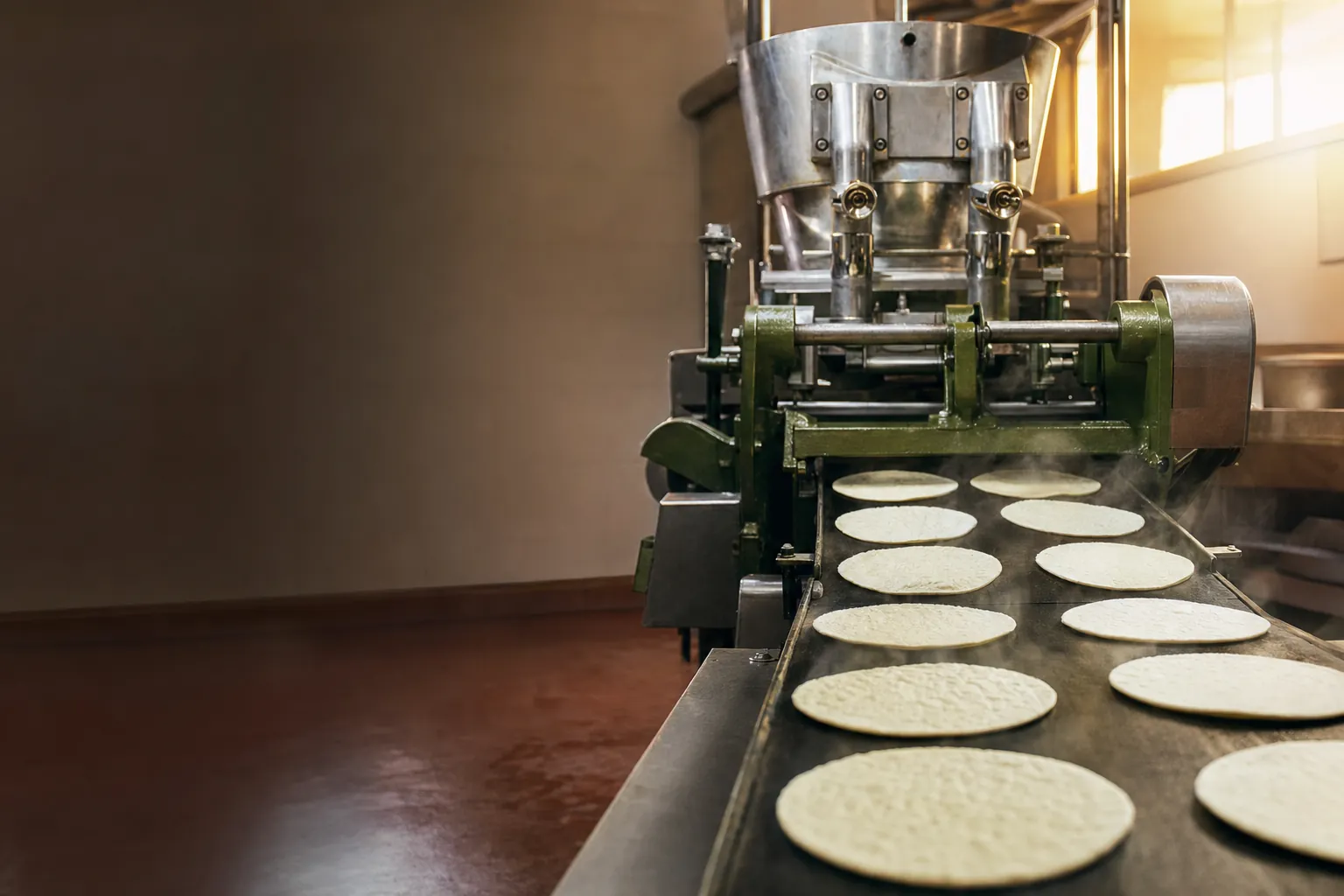 Máquina de tortillas de nuestra fábrica con tortillas recién hechas en la cinta