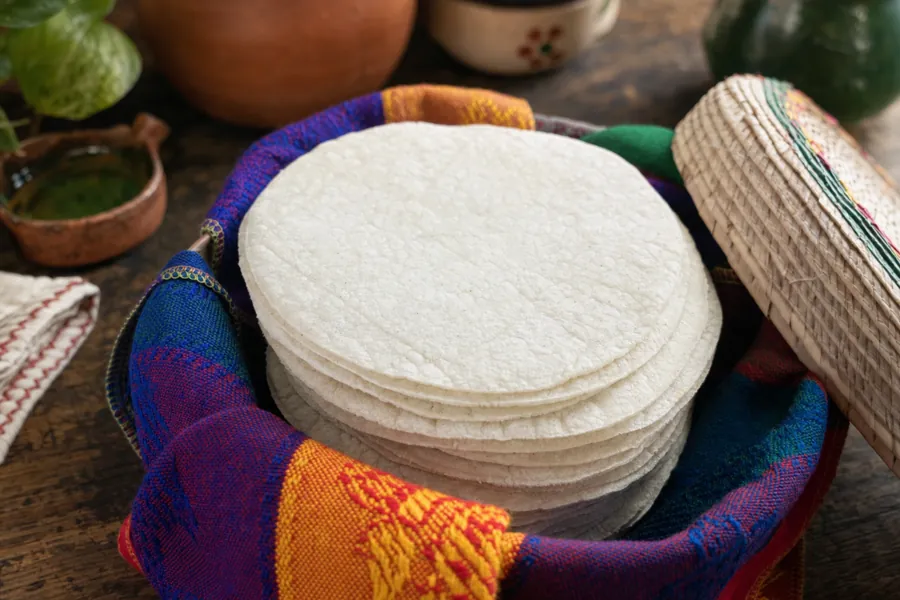 Tortillas de maíz blanco en un tortillero de tela